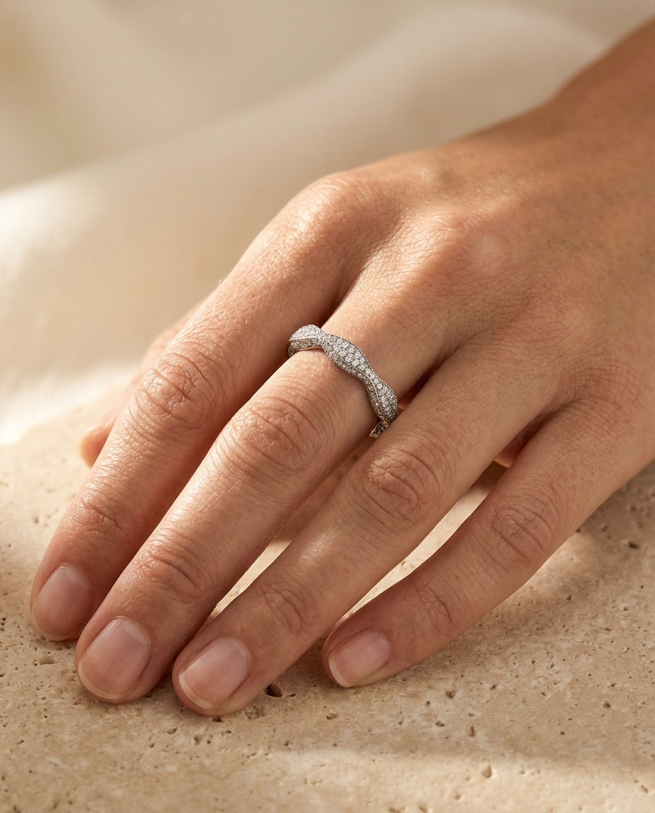 Éclat Ring by ALTUNA worn on the hand, resting on warm travertine in soft golden daylight