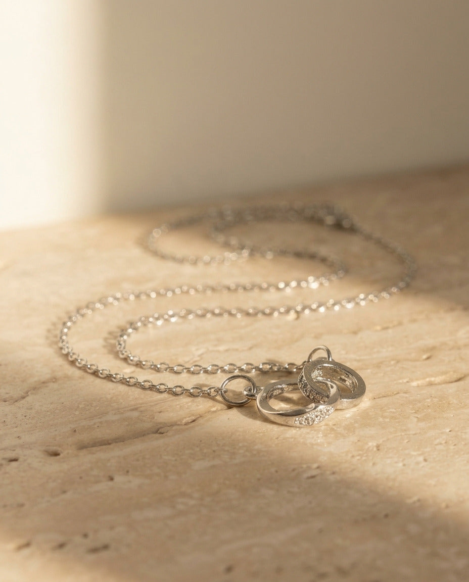 Armonia Necklace by ALTUNA - macro detail of the interlocking pave and polished rings on travertine