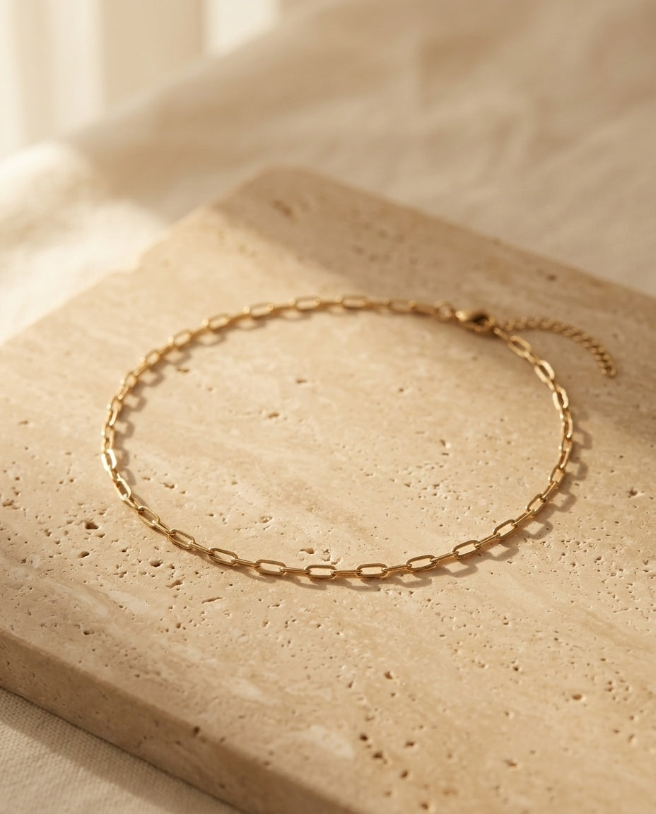 Céline Choker — gold paperclip chain choker on warm travertine, ALTUNA editorial