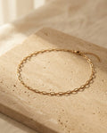 Céline Choker — gold paperclip chain choker on warm travertine, ALTUNA editorial