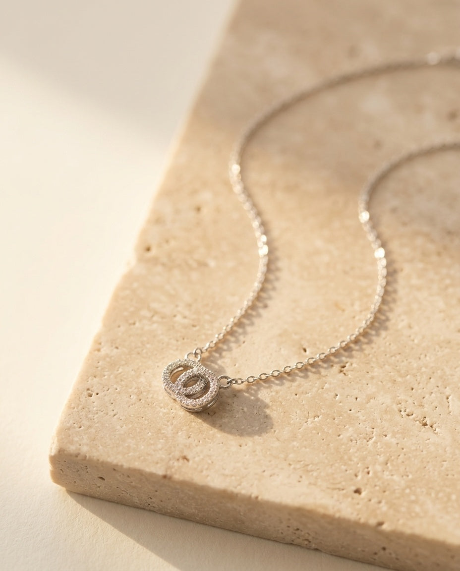 Claire Necklace by ALTUNA laid on warm beige travertine in soft golden light