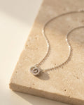 Claire Necklace by ALTUNA laid on warm beige travertine in soft golden light