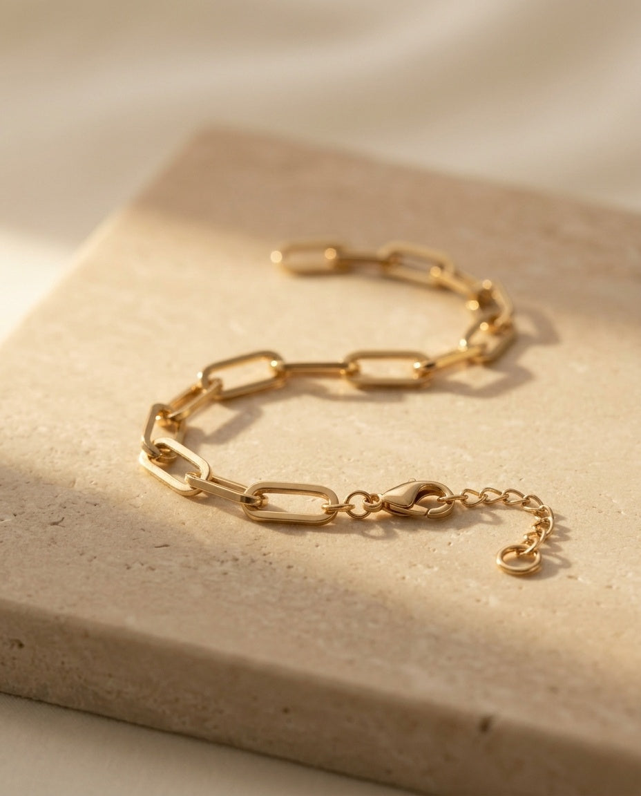 Doré Link Bracelet - polished gold paperclip chain, macro three-quarter detail on travertine