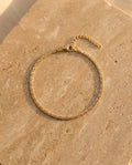 Éclisse Bracelet in gold on warm travertine