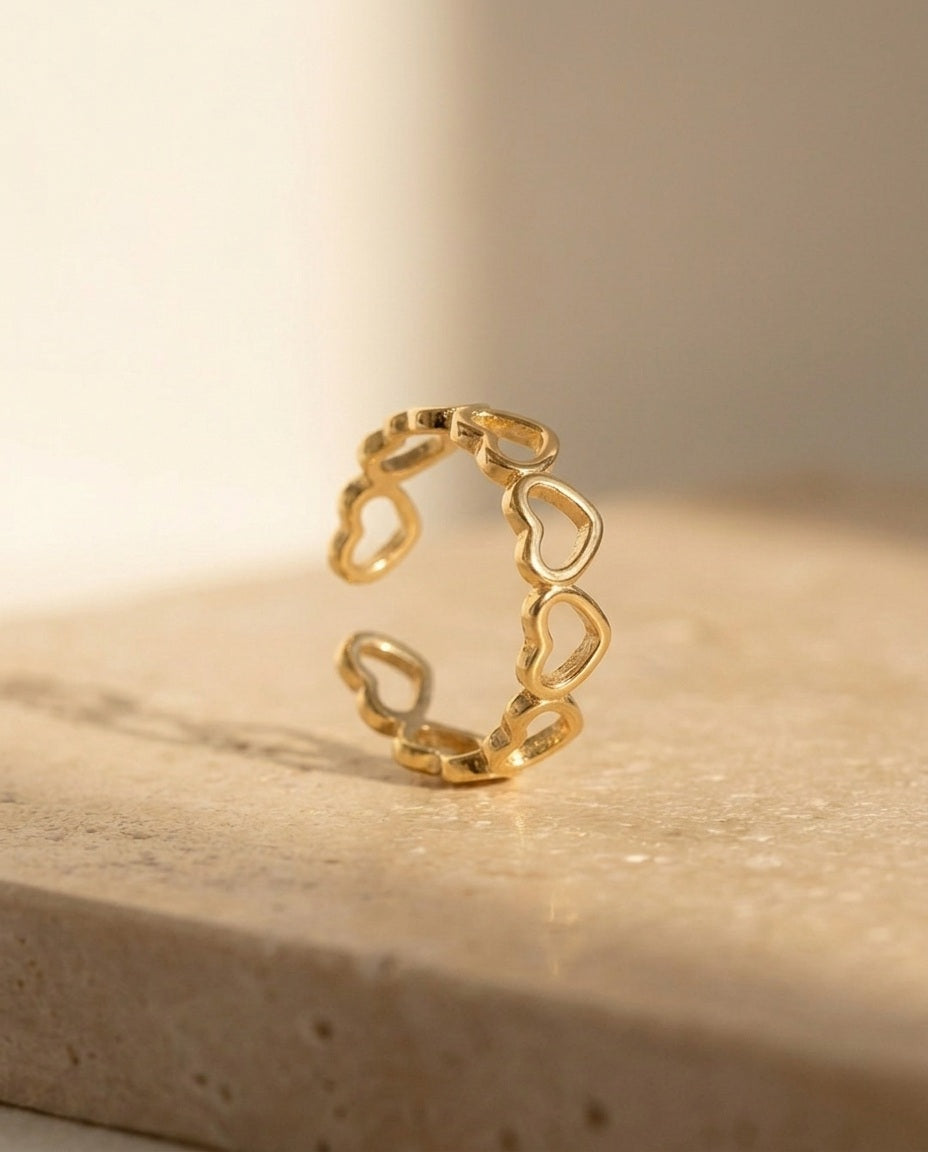 Endless Love Ring - macro detail of the yellow-gold open heart-outline band on travertine