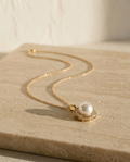 ALTUNA Promise Pearl Necklace — editorial product photography on warm beige travertine