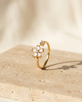 ALTUNA Flora Ring — editorial product photography on warm beige travertine
