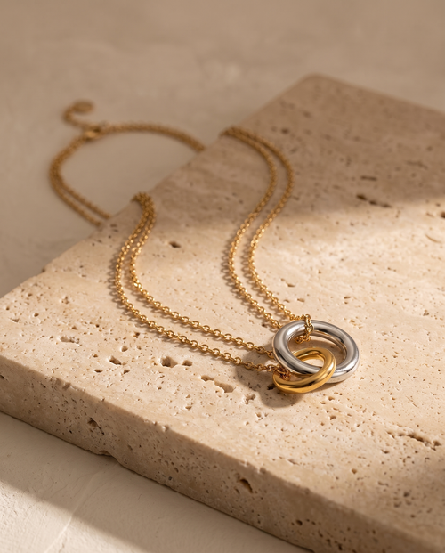 Endless Bond Necklace in silver and gold on travertine