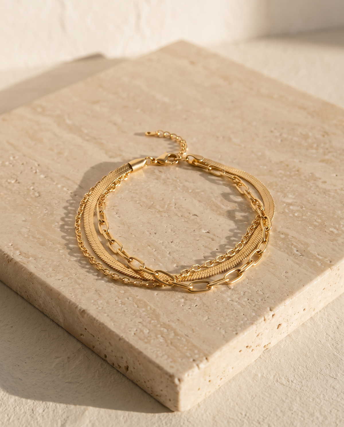 Triora Bracelet layered gold chains on travertine