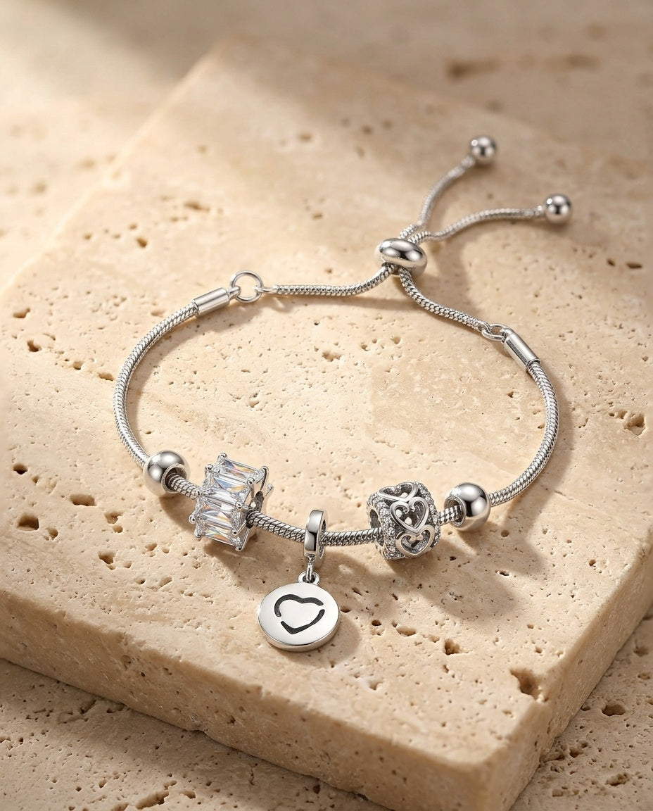 Love Charm Bracelet resting on warm beige travertine in soft golden light