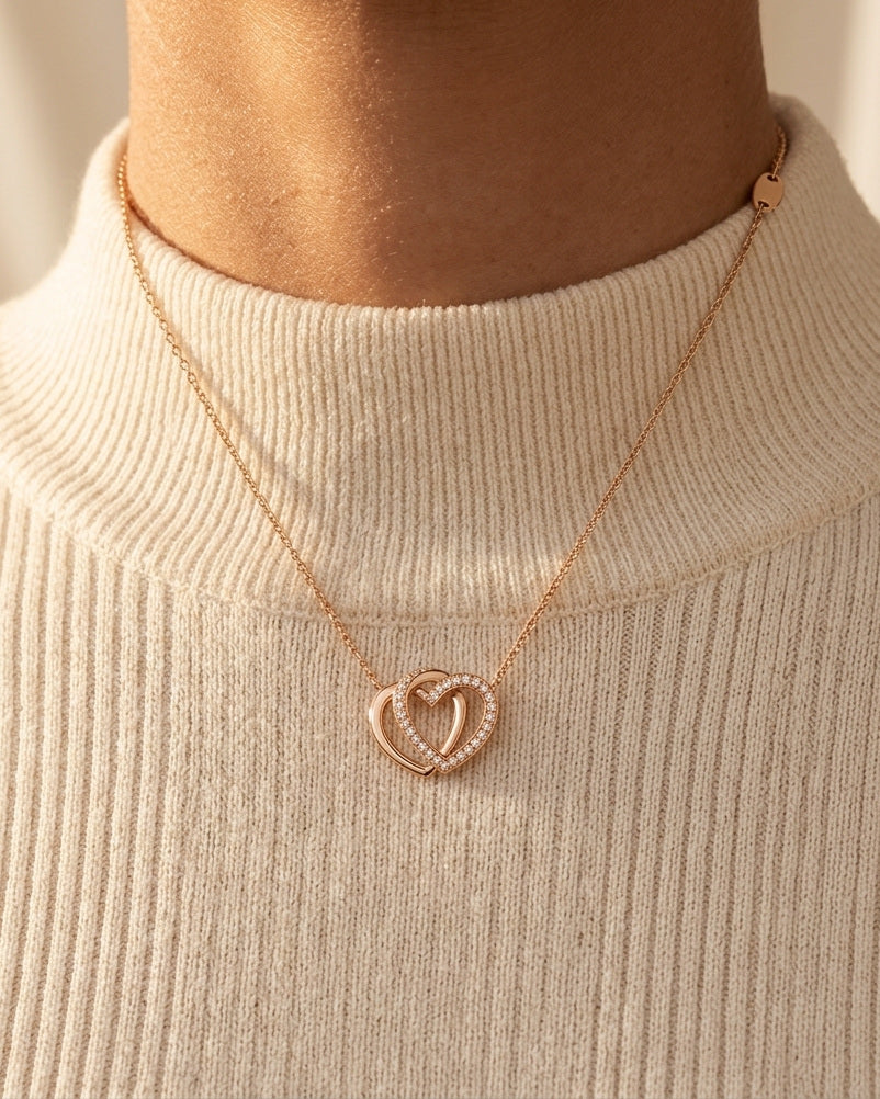 Lovebound Double Heart Necklace worn over a cream ribbed high-neck knit in warm golden light