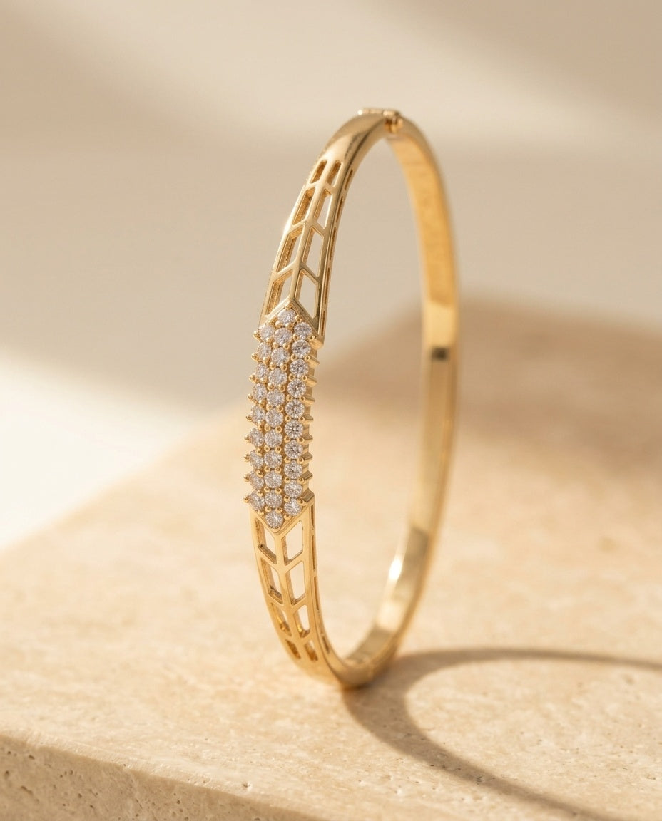 Lucia Bangle macro detail — three rows of pave stones and pierced openwork lattice panels in yellow gold on travertine