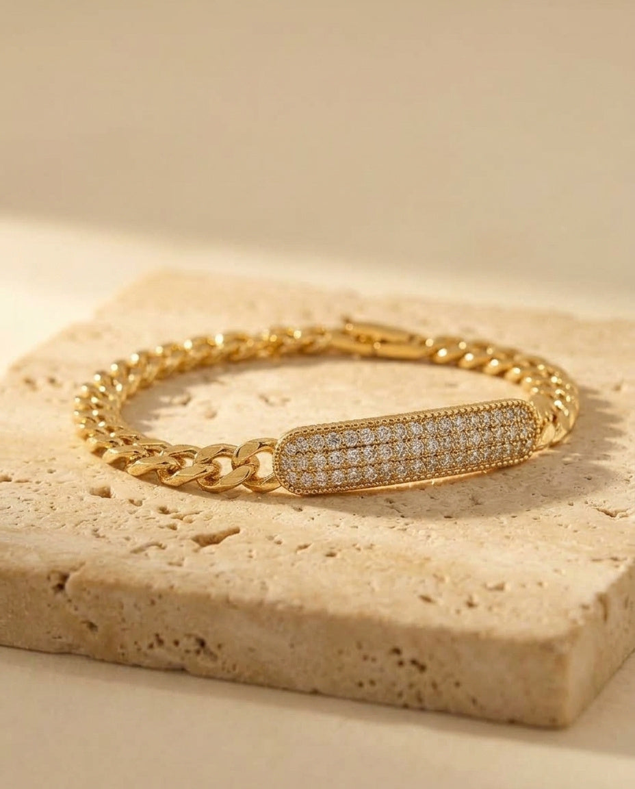 Opéra Bracelet — yellow-gold flat curb chain with pavé bar station, low-angle detail on travertine