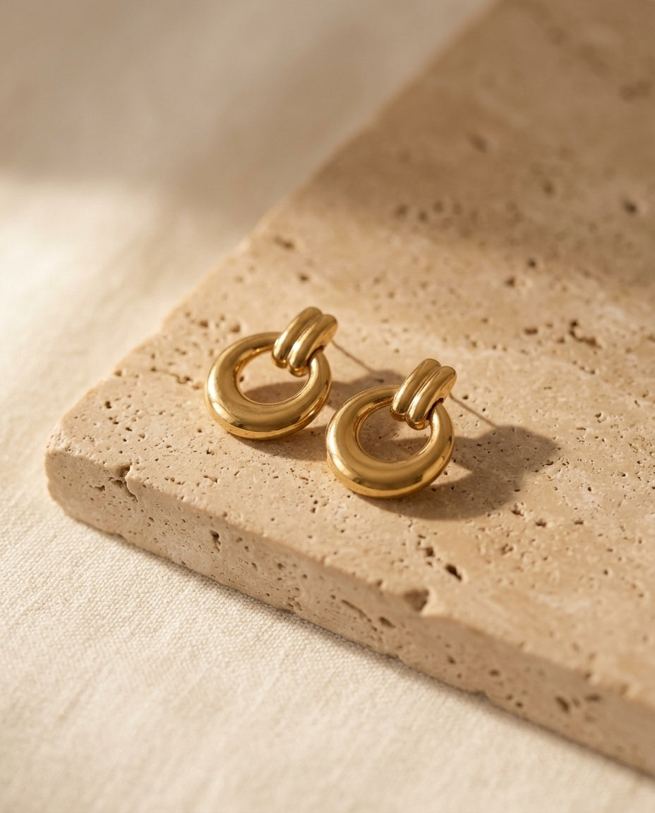 Oria Hoops by ALTUNA, gold-tone drop hoops on warm beige travertine