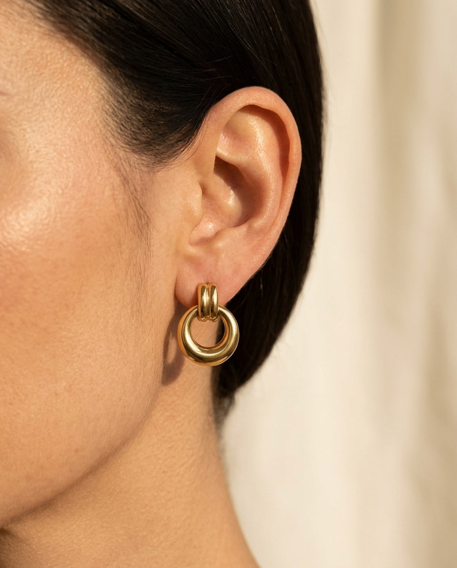 Oria Hoops by ALTUNA worn on the ear, polished gold-tone drop hoop in soft natural light