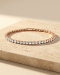 Roselle Bracelet in rose gold resting on warm beige travertine in golden sunlight