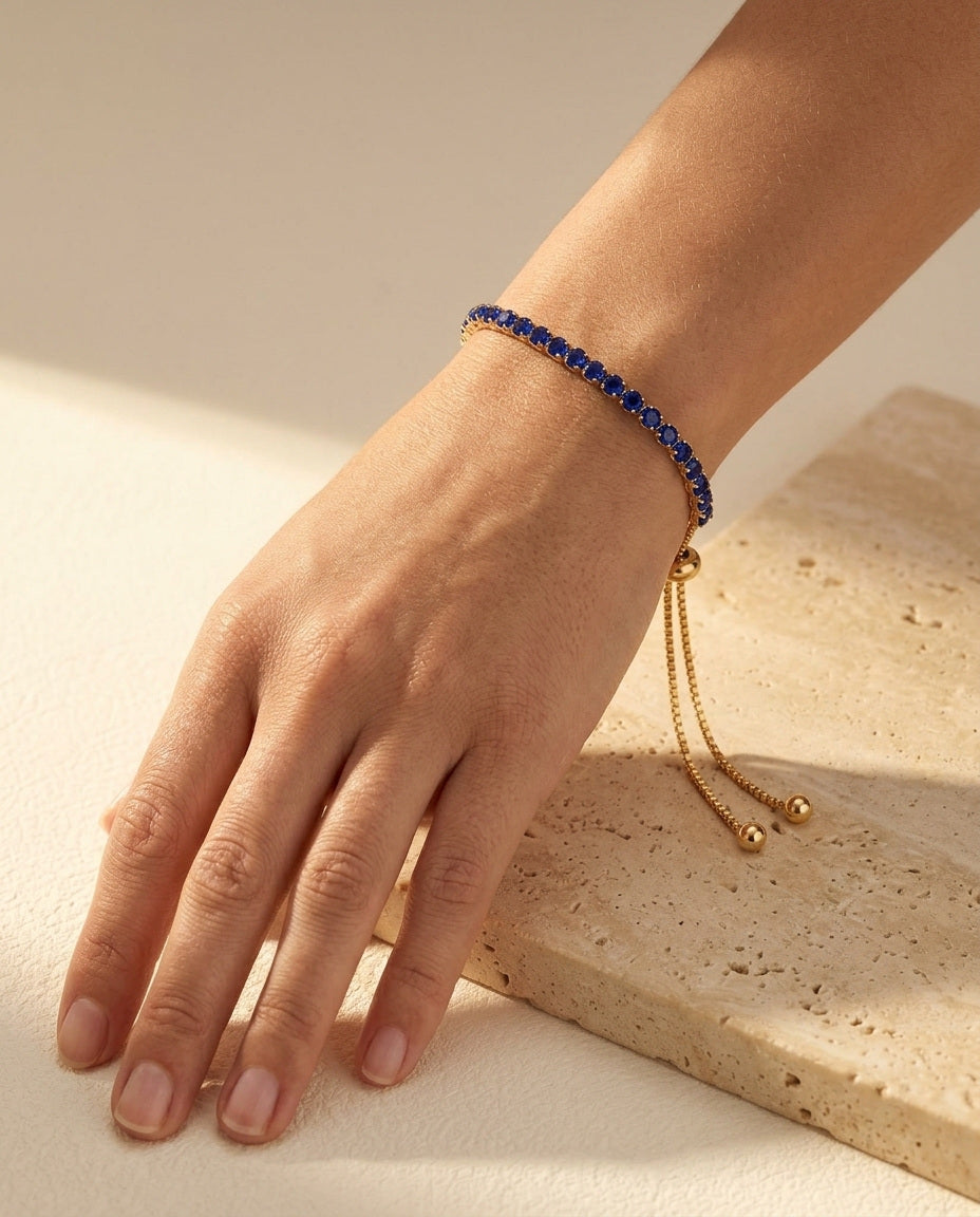 Seraphine Bracelet in Blue worn on the wrist - yellow gold tennis bracelet with royal blue stones and draping bolo tails