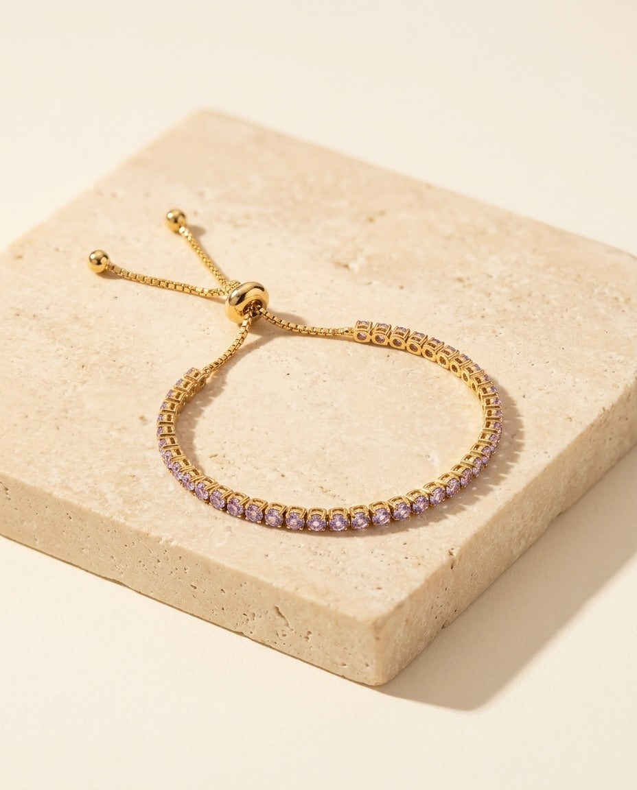 Seraphine Bracelet in Lavender - yellow gold tennis bracelet with pale violet stones on warm travertine