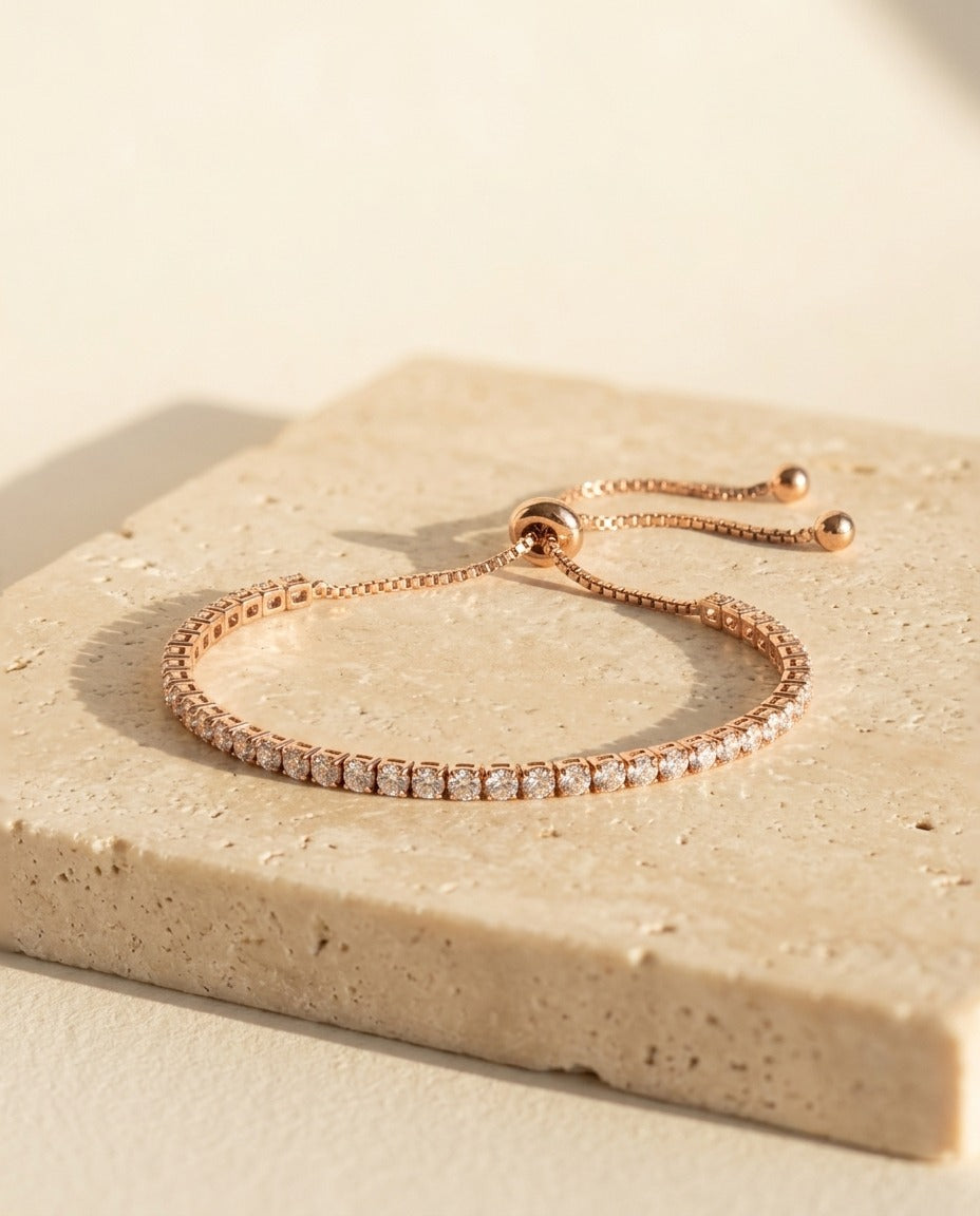 Seraphine Bracelet in Rose Gold - rose gold tennis bracelet with clear stones on warm travertine
