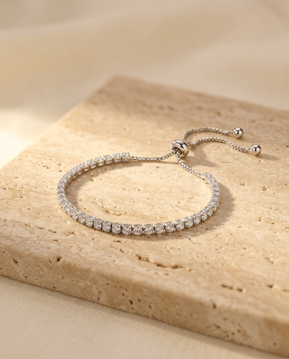 Seraphine Bracelet in Silver - bright silver tennis bracelet with clear stones on warm travertine