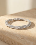 ALTUNA Spirale Bracelet resting on warm travertine in soft golden light