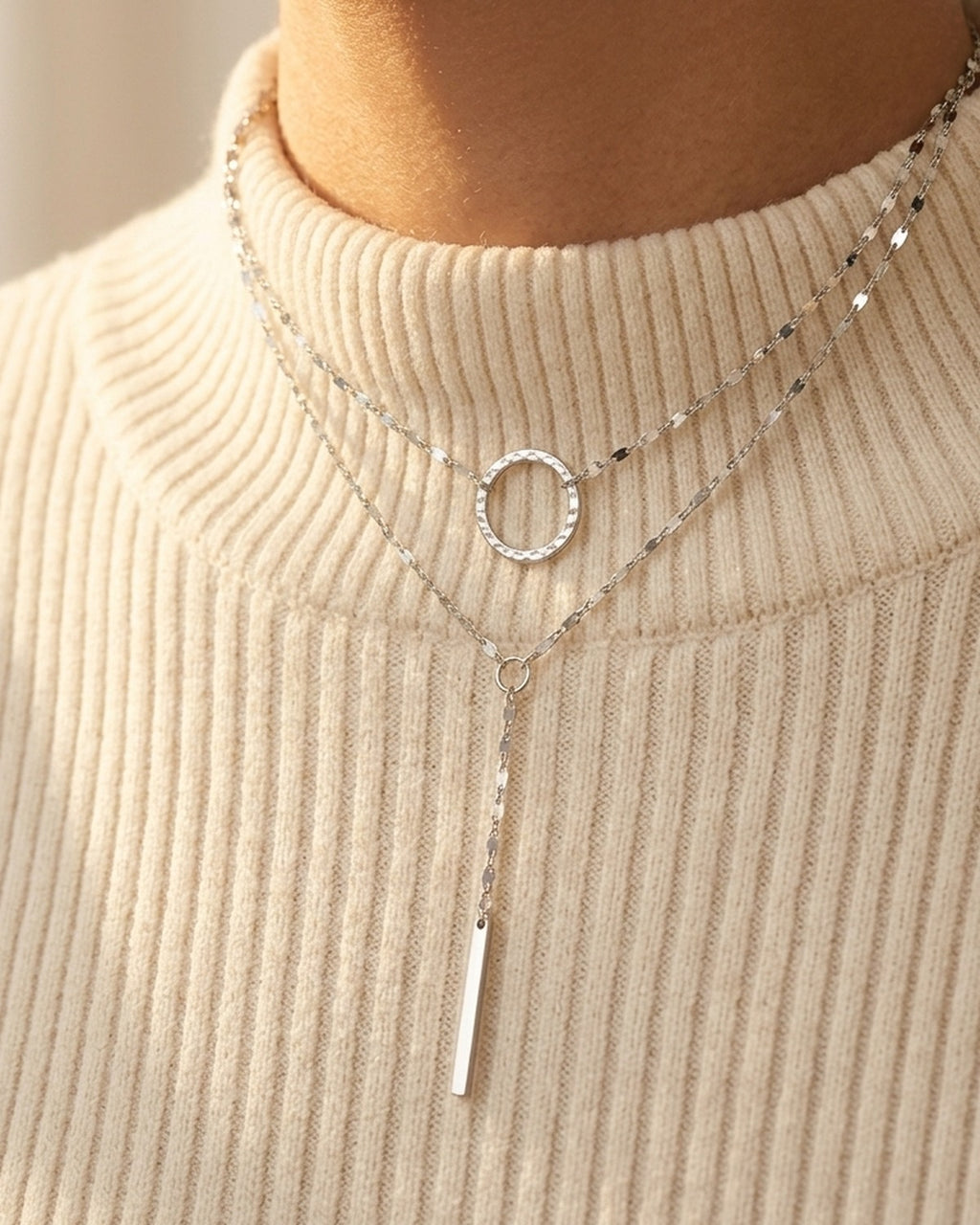 Sylara Necklace worn over an ivory ribbed turtleneck, layered silver chains with bar drop