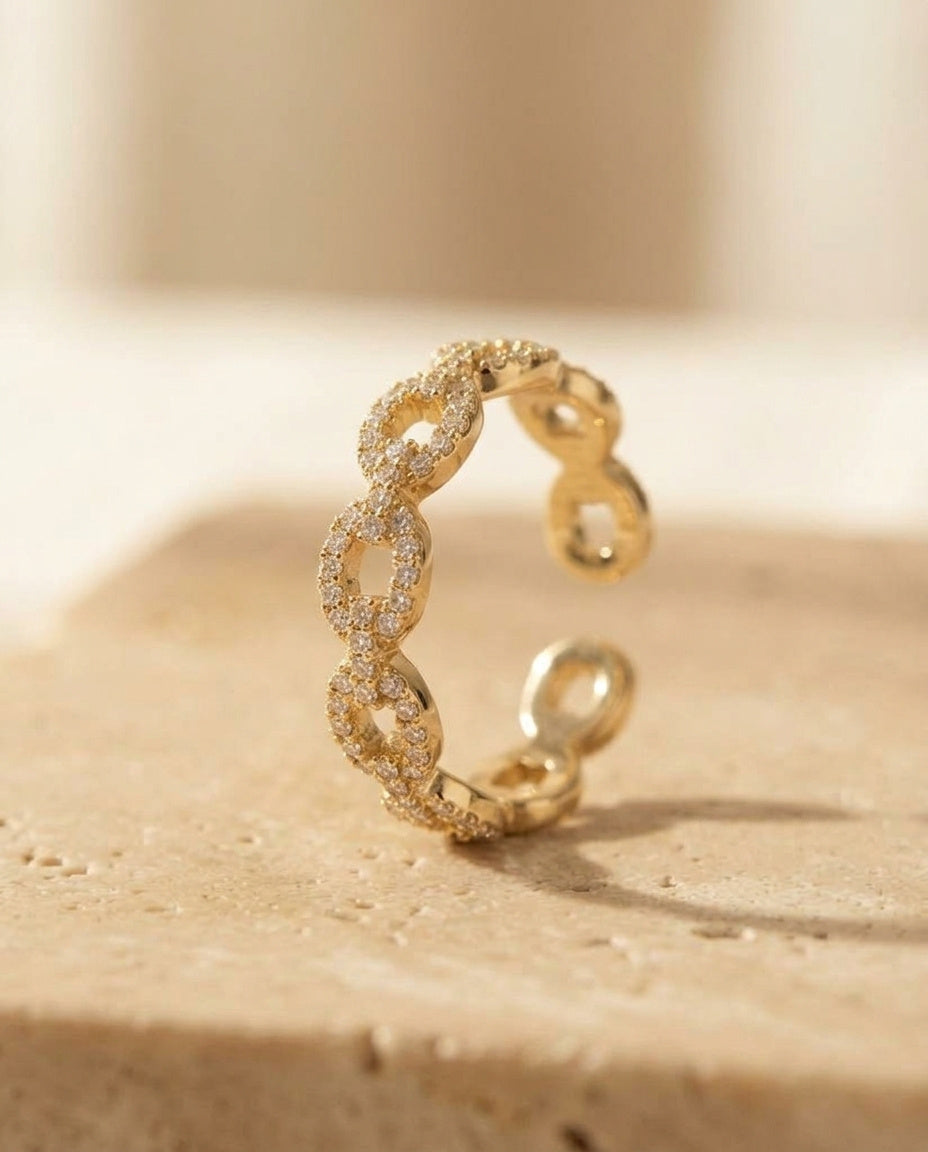 Velique Ring by ALTUNA — angled studio view of the pavé-set gold link band on warm travertine