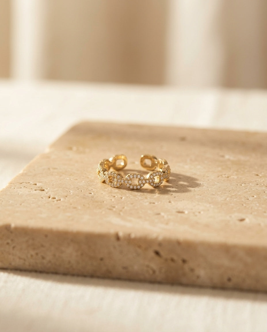 Velique Ring resting on warm beige travertine in soft golden light