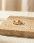 Velique Ring resting on warm beige travertine in soft golden light