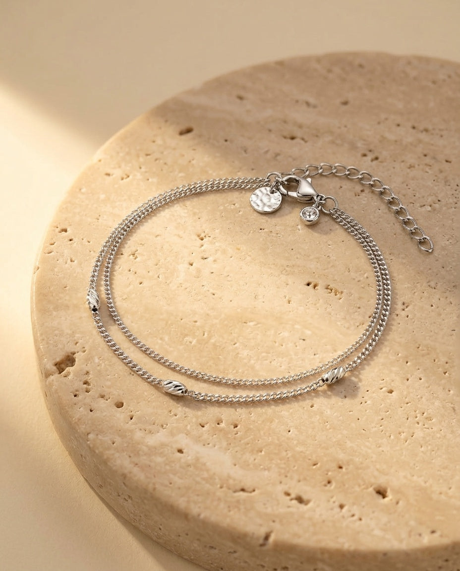 Véra Bracelet resting on warm beige travertine in soft golden light
